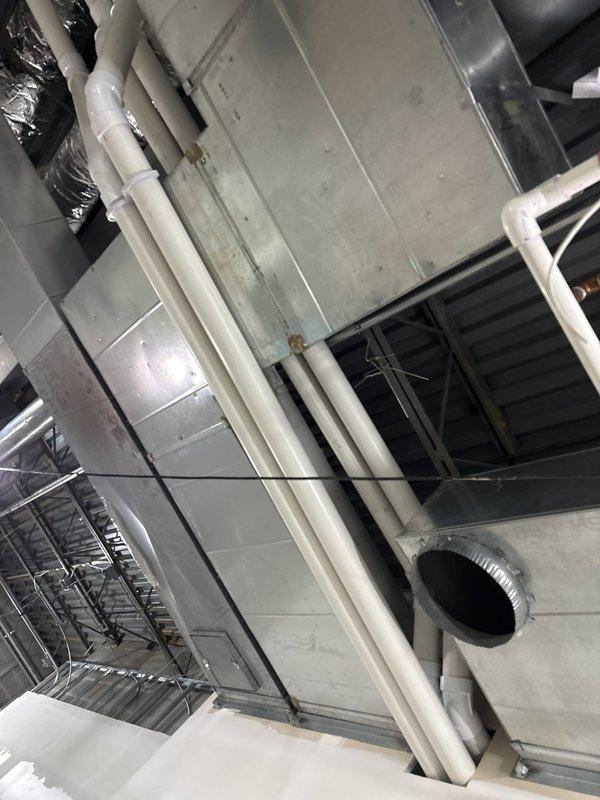 Completed installation of ductwork and flue piping on second floor mechanical space for commercial new construction project. Installed rigid and flexible ductwork with proper support brackets and strapping, routed PVC condensate drain lines, and ensured all mechanical components were properly secured and positioned according to specifications.