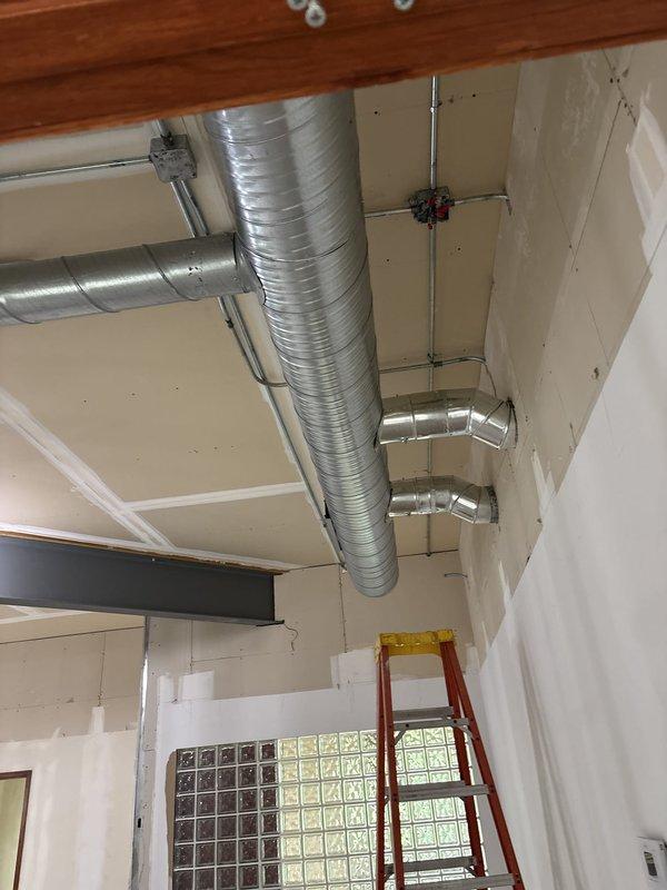 Completed installation of ductwork and flue piping on second floor mechanical space for commercial new construction project. Installed rigid and flexible ductwork with proper support brackets and strapping, routed PVC condensate drain lines, and ensured all mechanical components were properly secured and positioned according to specifications.