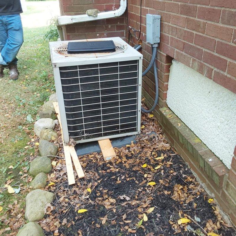 Completed full AC system retrofit at residential property. Installed new outdoor condensing unit on wooden blocks with proper ground preparation and positioning adjacent to existing electrical disconnect and brick foundation. Interior installation included integration with existing furnace system in basement utility area, with new refrigerant line sets and proper connection to ductwork infrastructure.