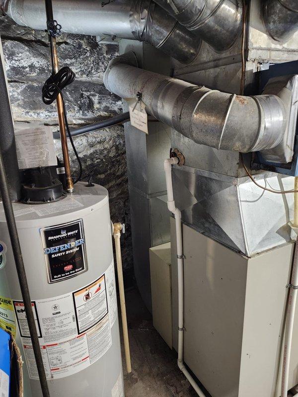 Completed AC retrofit installation in residential basement mechanical room. Installed new air conditioning coil integrated with existing beige furnace unit, coordinating with current ductwork configuration and water heater placement in confined utility space. System tested and operational upon completion.