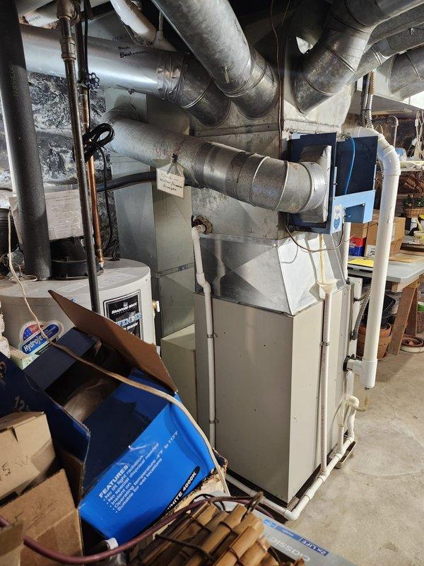 Completed AC retrofit installation in residential basement mechanical room. Installed new air conditioning coil integrated with existing beige furnace unit, coordinating with current ductwork configuration and water heater placement in confined utility space. System tested and operational upon completion.