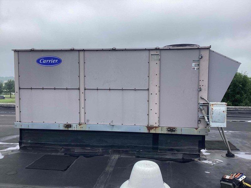 Responded to no cooling complaint on Carrier rooftop unit. Upon arrival, performed comprehensive diagnostic evaluation of system previously diagnosed with refrigerant leak and compressor failure. Utilized digital multimeter to test compressor electrical components and verify operational status. Conducted visual inspection of compressor assembly, noting significant corrosion on compressor dome and oxidation on copper refrigerant lines consistent with outdoor exposure and age of equipment. Examined all refrigerant line connections and assessed system for potential leak points. Documented current equipment condition with photographs showing weathered compressor unit, associated refrigerant piping, and overall RTU cabinet condition. Confirmed system requires compressor replacement as previously diagnosed due to component failure and recommended addressing refrigerant leak prior to compressor installation to ensure proper system operation upon repair completion.