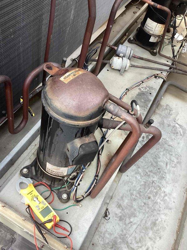 Responded to no cooling complaint on Carrier rooftop unit. Upon arrival, performed comprehensive diagnostic evaluation of system previously diagnosed with refrigerant leak and compressor failure. Utilized digital multimeter to test compressor electrical components and verify operational status. Conducted visual inspection of compressor assembly, noting significant corrosion on compressor dome and oxidation on copper refrigerant lines consistent with outdoor exposure and age of equipment. Examined all refrigerant line connections and assessed system for potential leak points. Documented current equipment condition with photographs showing weathered compressor unit, associated refrigerant piping, and overall RTU cabinet condition. Confirmed system requires compressor replacement as previously diagnosed due to component failure and recommended addressing refrigerant leak prior to compressor installation to ensure proper system operation upon repair completion.