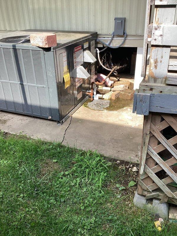 Responded to warranty call for recently installed mobile home package unit with reported water leakage from interior vent. Upon arrival, inspected outdoor package unit positioned on cracked concrete pad and found unit operational but noted debris on top of equipment. Conducted interior inspection and located floor register where water intrusion was reported. Determined condensate drainage issue causing water to back up through ductwork and discharge at interior vent location. Cleared condensate line obstruction, verified proper drain flow, and tested system operation to confirm resolution. Unit cycling properly with no further leakage observed at time of departure.