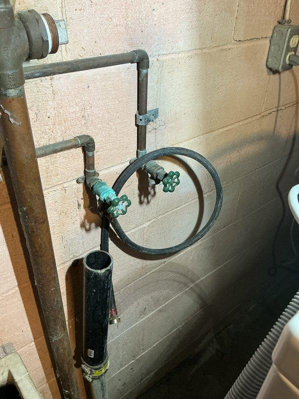 Conducted site assessment of residential plumbing system in basement utility area. Evaluated existing boiler drain valves on utility sink assembly requiring replacement due to age and corrosion. Inspected gas line routing for stove installation and determined flex line connection points. Assessed water heater flex line connector showing signs of wear and recommended replacement for safety compliance. Documented current configuration of utility sink plumbing mounted on cinderblock wall, including shut-off valves and filter assembly. Examined Rheem Performance water heater installation with associated piping connections and provided estimate for requested repairs and installations.