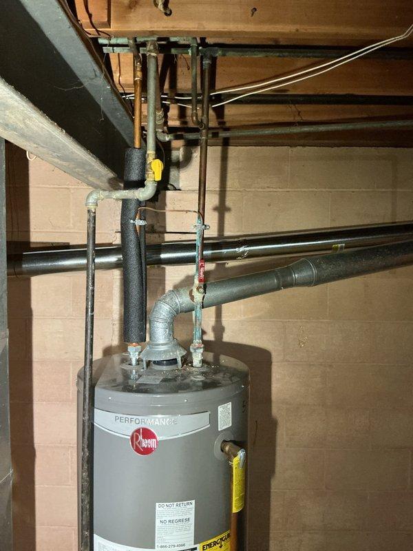 Conducted site assessment of residential plumbing system in basement utility area. Evaluated existing boiler drain valves on utility sink assembly requiring replacement due to age and corrosion. Inspected gas line routing for stove installation and determined flex line connection points. Assessed water heater flex line connector showing signs of wear and recommended replacement for safety compliance. Documented current configuration of utility sink plumbing mounted on cinderblock wall, including shut-off valves and filter assembly. Examined Rheem Performance water heater installation with associated piping connections and provided estimate for requested repairs and installations.
