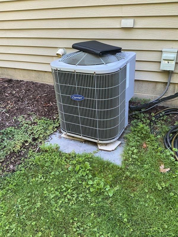 Completed full HVAC system retrofit including furnace and air conditioning equipment replacement. Installed new Carrier outdoor condensing unit on concrete pad with proper leveling materials and positioned unit against exterior wall in mulched landscape area. Interior installation included new furnace/air handler unit in basement utility area with all electrical connections, circuit boards, and wiring harnesses properly terminated and secured with zip ties to terminal blocks. Verified all internal electrical components including capacitors and relays are functioning correctly, confirmed proper drainage system connections with white PVC condensate piping, and installed flexible metal conduit and junction box for electrical service. System tested and operational.