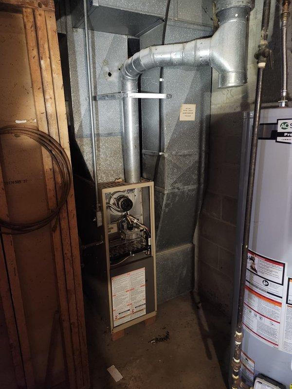 Completed furnace installation in basement mechanical room. Installed new beige furnace unit with exposed blower assembly and motor, connected to galvanized metal ductwork system with rectangular supply ducts extending from unit. Secured all ductwork connections with proper sealing and mechanical fasteners, routed supply duct through basement ceiling joists using metal strapping for support. Verified proper clearances from existing water heater and other mechanical equipment, ensured all manufacturer specifications met for installation requirements. System tested and operational upon completion.
