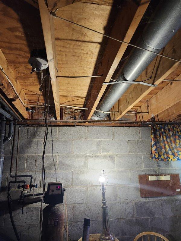 Completed furnace installation in basement mechanical room. Installed new beige furnace unit with exposed blower assembly and motor, connected to galvanized metal ductwork system with rectangular supply ducts extending from unit. Secured all ductwork connections with proper sealing and mechanical fasteners, routed supply duct through basement ceiling joists using metal strapping for support. Verified proper clearances from existing water heater and other mechanical equipment, ensured all manufacturer specifications met for installation requirements. System tested and operational upon completion.