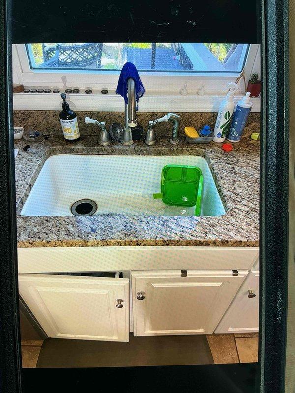 Conducted on-site evaluation for kitchen sink replacement in granite countertop installation. Assessed existing white undermount basin, chrome faucet assembly with separate handles, and under-sink plumbing configuration including garbage disposal unit with dishwasher connection. Documented current conditions and provided comprehensive estimate for fixture replacement as requested second opinion.