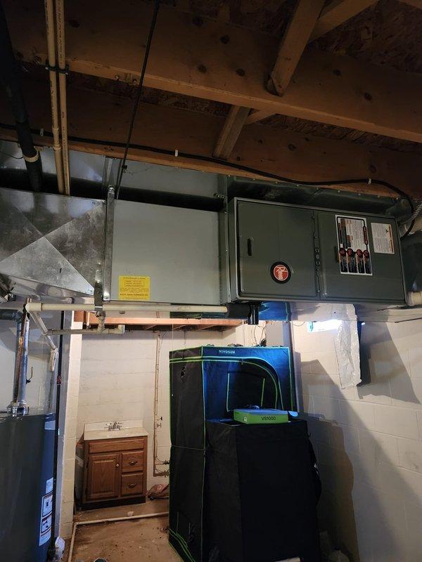 Completed installation of new residential air conditioning system including outdoor condensing unit and indoor evaporator coil. Positioned outdoor unit on concrete pad adjacent to home foundation with proper clearances, installed electrical disconnect box on exterior wall, and ran conduit for power supply. Inside basement utility area, installed new evaporator coil and integrated system with existing ductwork near water heater location. Verified all electrical connections to main panel, tested system operation, and confirmed proper refrigerant charge and airflow throughout. Unit operational and cooling effectively.