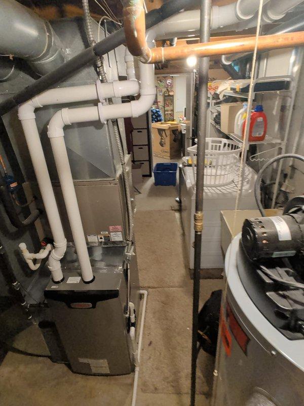 Completed furnace retrofit in residential basement utility room. Installed modern gray HVAC unit with associated white PVC condensate drain and ventilation piping, including multiple elbows and joints for proper routing. Connected black flexible ductwork and metallic flex duct to system, ensuring all connections were secure and code-compliant. Unit is operational and functioning as designed.