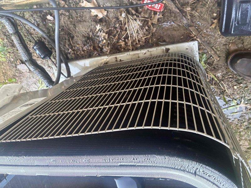 Responded to no cooling complaint in 5th and 6th grade classrooms while library was overcooling. Upon inspection, found RTU condenser unit with heavily soiled protective grille and condenser coil covered in dust, dirt, and debris accumulation, restricting airflow and reducing system efficiency. Cleaned condenser coil and grille, removed organic debris from unit vicinity, verified proper airflow restoration, and confirmed system operation returned to normal parameters with balanced cooling throughout affected zones.