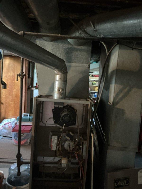 Conducted comprehensive assessment of existing basement furnace system and ductwork infrastructure to provide estimate for adding central air conditioning and potential complete HVAC system replacement. Evaluated current gray metal furnace unit with exposed blower motor and internal components, inspected existing galvanized ductwork distribution throughout basement ceiling, and assessed structural layout for optimal AC integration. Documented equipment specifications, measured available space for condenser placement, reviewed electrical capacity requirements, and analyzed ductwork modifications needed to accommodate cooling system installation.