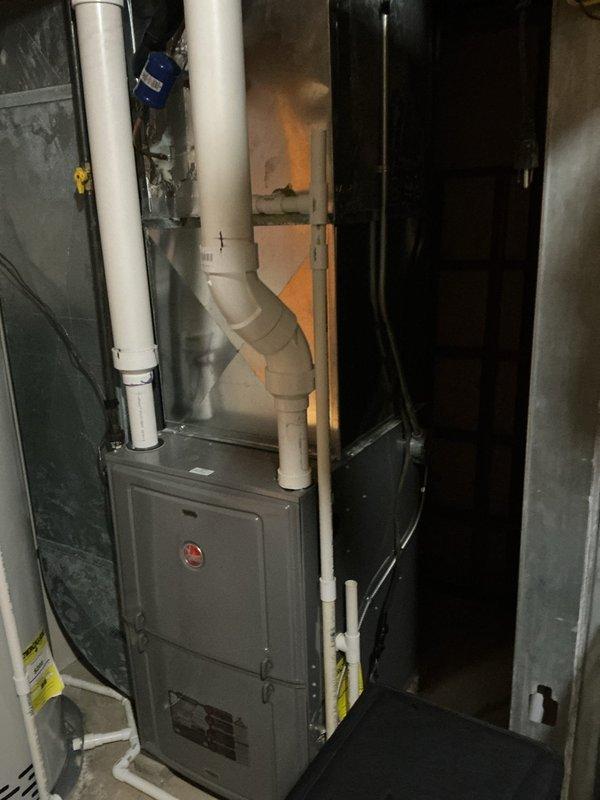Completed full air conditioning system replacement at residential property. Installed new outdoor condenser unit on existing concrete pad with proper clearances maintained from surrounding landscaping and hostas. Mounted new electrical disconnect box on exterior wall with code-compliant conduit routing from house to unit. Interior installation included new air handler positioned in basement mechanical room alongside existing furnace and water heater in confined utility space. Routed new white PVC condensate drain lines vertically with proper pitch and termination. All refrigerant lines connected and pressure tested, system charged to manufacturer specifications. Verified electrical connections at both indoor and outdoor units, tested all safety controls and disconnect functionality. System startup completed with airflow measurements confirming proper CFM delivery. Verified cooling operation through complete cycle, checked temperature split across coil within acceptable range. All equip