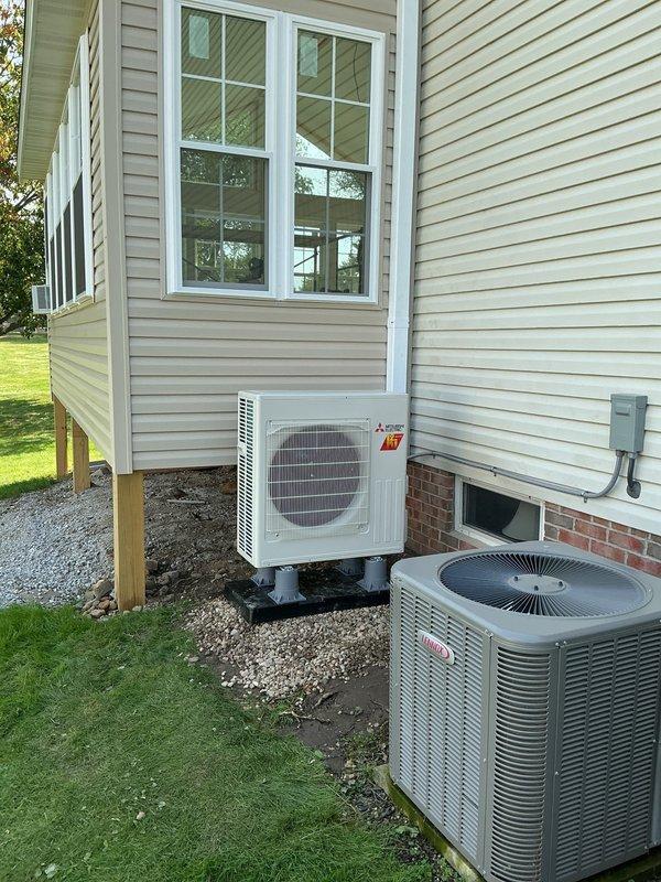 Completed rough-in installation of Mitsubishi ductless mini-split heat pump system in new construction residential property. Mounted indoor wall unit on interior wall below vaulted ceiling with proper clearances, installed exterior condenser unit on pad with appropriate spacing from existing Lennox central air system, and ran refrigerant line set and electrical connections between indoor and outdoor components. System is ready for final startup and commissioning upon completion of finish work.