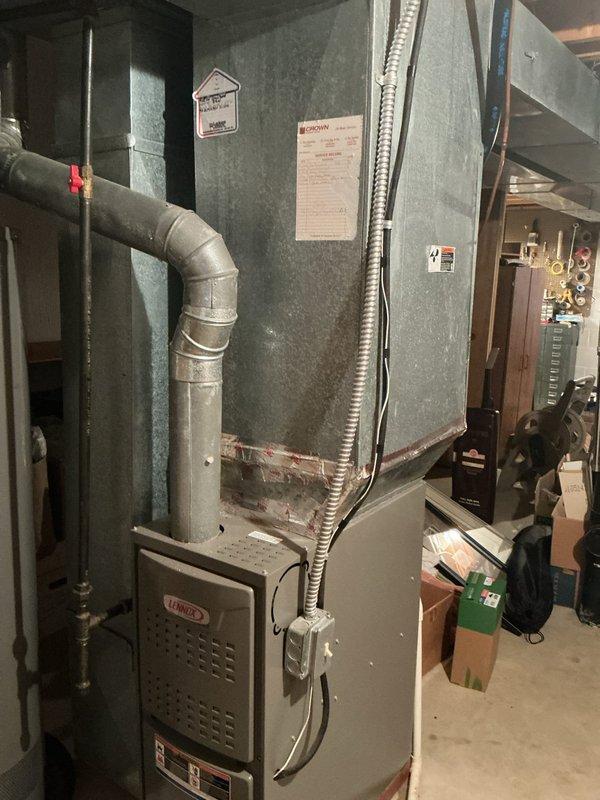 Completed full air conditioning system retrofit at residential property. Installed new York brand outdoor condensing unit on concrete pad with proper electrical disconnect and conduit routing through exterior siding. Interior installation included Lennox furnace/air handler unit with associated ductwork, exhaust venting, and refrigerant line connections in basement utility area. All equipment positioned per manufacturer specifications with appropriate clearances for service access and airflow requirements.