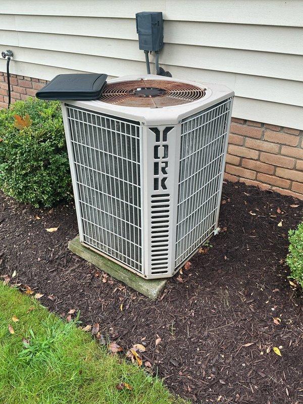 Completed full air conditioning system retrofit at residential property. Installed new York brand outdoor condensing unit on concrete pad with proper electrical disconnect and conduit routing through exterior siding. Interior installation included Lennox furnace/air handler unit with associated ductwork, exhaust venting, and refrigerant line connections in basement utility area. All equipment positioned per manufacturer specifications with appropriate clearances for service access and airflow requirements.