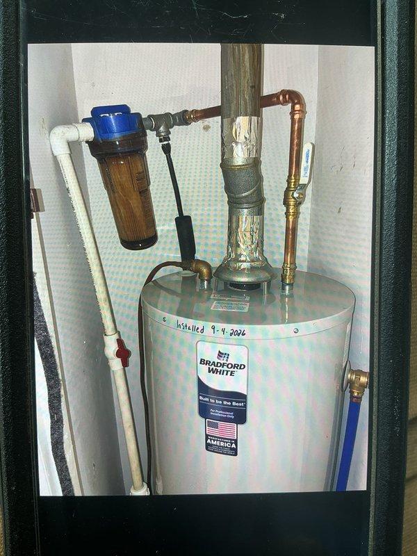 Replaced existing Bradford White water heater that was originally installed in 2002 with a new unit. Removed old water heater from utility closet location and installed replacement Bradford White tank-style water heater. Connected copper supply lines with brass fittings to inlet and outlet ports at top of unit. Installed pressure relief valve with proper discharge piping. Reconnected existing water filtration system with white PVC piping to cold water supply line. Verified all plumbing connections for proper seal and tested unit operation to ensure adequate hot water delivery and system functionality.