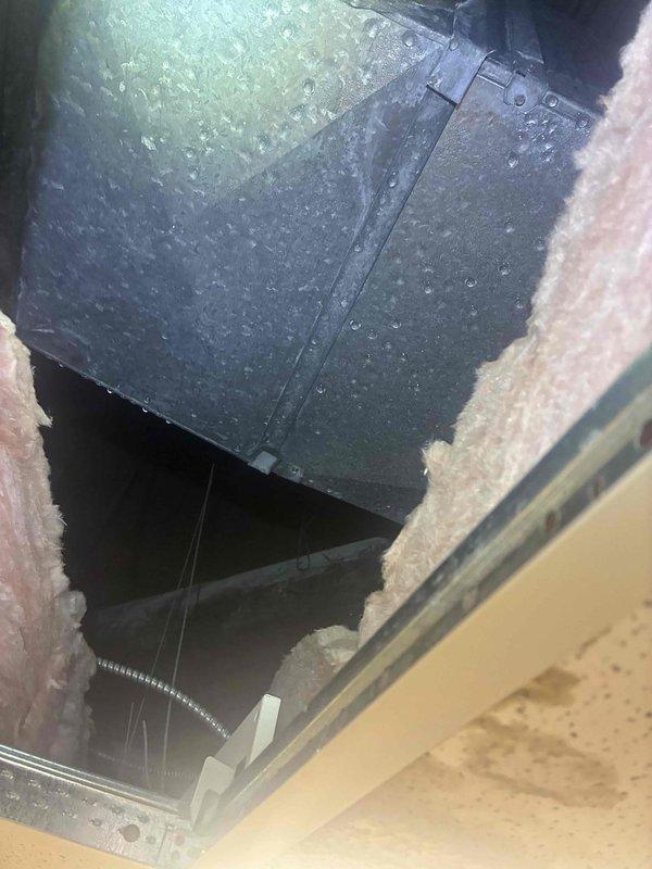 Responded to service call for commercial HVAC system with multiple zone temperature discrepancies. Found significant condensation and water leakage from ductwork in ceiling space above one zone. Inspected York thermostat showing 70°F setpoint with cooling mode active. Documented excessive condensation on main supply duct with water droplets covering entire surface, indicating inadequate insulation and likely cause of ceiling leak. System requires duct insulation repair or replacement and further evaluation of refrigerant charge and airflow balance across all zones to address uneven cooling performance between areas.