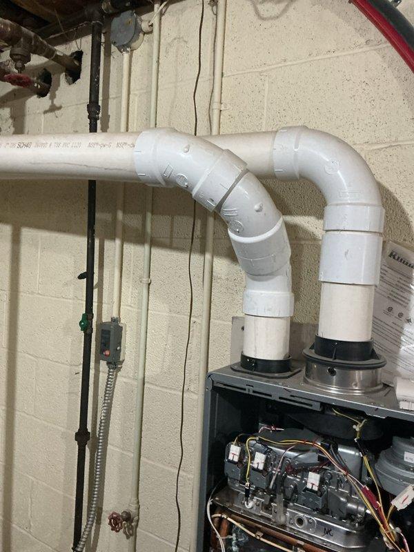 Conducted on-site assessment of existing water heating system in basement utility area to provide estimate for tankless water heater installation. Evaluated current plumbing configuration including copper supply lines, existing tank-style water heater, gas connections, and venting system. Photographed existing equipment layout, wall-mounted HVAC components, PVC drainage piping, and available installation space to determine optimal placement and required modifications for tankless unit conversion.