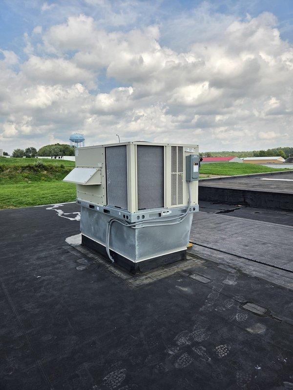 Conducted new construction site visit to document installation of commercial rooftop HVAC package unit and associated indoor equipment. Photographed exterior rooftop unit mounted on curb adapter with proper elevation above roof membrane, confirmed unit positioning and clearances meet specifications. Inspected and documented interior air handling equipment mounted to ceiling structure with PVC condensate drainage system and electrical connections in place.