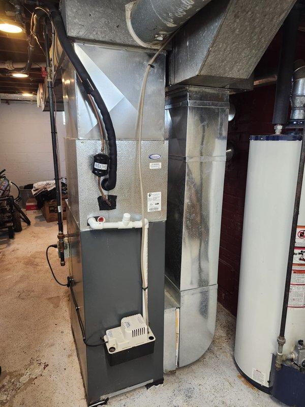 # HVAC Complete System Installation

Successfully completed a full HVAC system installation in residential basement mechanical room. Installed new Goodman 80% AFUE gas furnace with flue liner to replace existing heating equipment. Unit positioned on concrete floor with proper clearances for service access and safety compliance.

Connected furnace to existing galvanized ductwork system running overhead through ceiling joists. Installed condensate pump at furnace base to handle moisture removal. Ran black flexible ductwork and electrical conduit from unit to ceiling connections. Ensured all duct connections properly sealed and secured to prevent air leakage.

Completed all electrical connections per manufacturer specifications and local code requirements. Installed thermostat wiring and verified proper communication between control system and furnace. Tested all safety controls including limit switches, flame sensor, and pressure switches.

Commissioned system with full startup procedure
