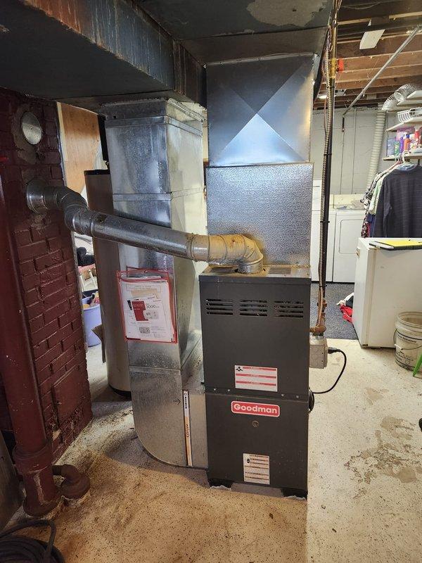 # HVAC Complete System Installation

Successfully completed a full HVAC system installation in residential basement mechanical room. Installed new Goodman 80% AFUE gas furnace with flue liner to replace existing heating equipment. Unit positioned on concrete floor with proper clearances for service access and safety compliance.

Connected furnace to existing galvanized ductwork system running overhead through ceiling joists. Installed condensate pump at furnace base to handle moisture removal. Ran black flexible ductwork and electrical conduit from unit to ceiling connections. Ensured all duct connections properly sealed and secured to prevent air leakage.

Completed all electrical connections per manufacturer specifications and local code requirements. Installed thermostat wiring and verified proper communication between control system and furnace. Tested all safety controls including limit switches, flame sensor, and pressure switches.

Commissioned system with full startup procedure