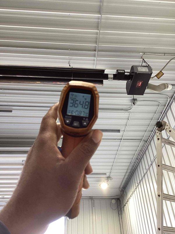 Responded to service call for commercial tube heater that experienced operational issues at end of previous heating season. Performed diagnostic inspection of unit mounted in overhead warehouse space behind retail establishment. Utilized infrared thermometer to assess temperature readings and evaluate system performance, documenting current conditions with thermal measurements showing subzero readings indicating potential heating element or combustion issues. Inspected flexible ductwork connections, mounting hardware, and overall unit installation in corrugated metal ceiling structure to identify cause of malfunction and determine necessary repairs.