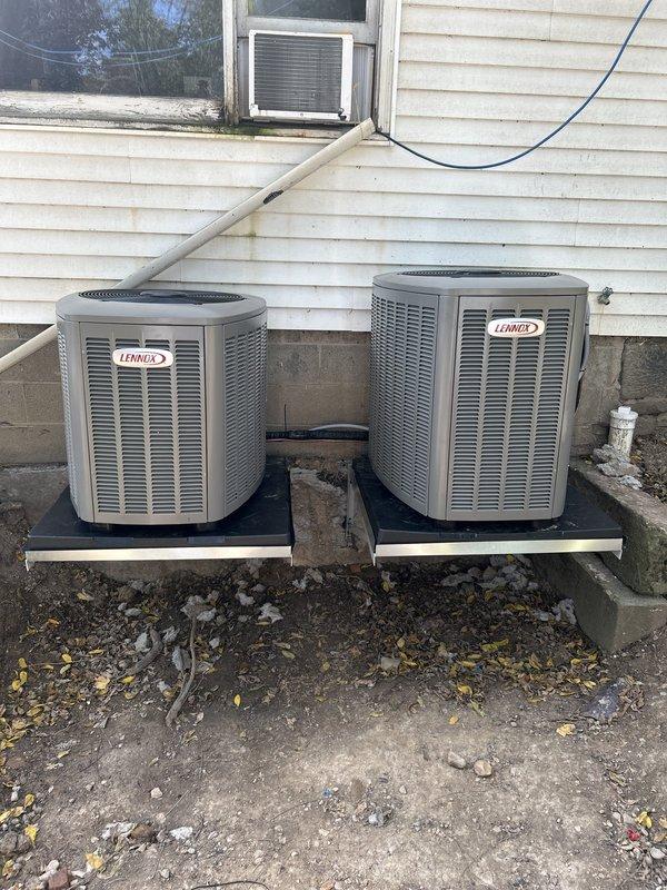 Completed installation of second Lennox outdoor condensing unit as part of dual-system HVAC setup. Both units mounted on shared black platform against exterior foundation with proper clearances maintained. Installed refrigerant line set with secure wall mounting, connected electrical service with exterior disconnect box, and verified proper drainage routing. Performed preventive maintenance inspection on existing system to ensure optimal performance of both units.