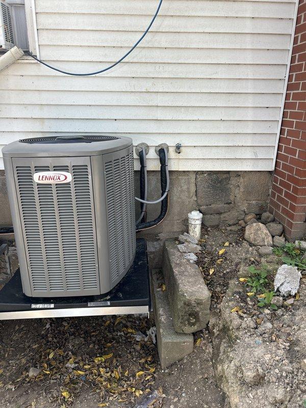 Completed installation of second Lennox outdoor condensing unit as part of dual-system HVAC setup. Both units mounted on shared black platform against exterior foundation with proper clearances maintained. Installed refrigerant line set with secure wall mounting, connected electrical service with exterior disconnect box, and verified proper drainage routing. Performed preventive maintenance inspection on existing system to ensure optimal performance of both units.
