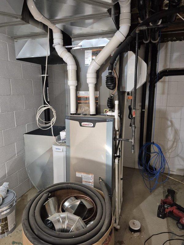 Completed installation of ductwork in residential basement mechanical room that had been intentionally omitted prior to spray foam insulation application. Connected stainless steel plenum and white PVC piping system to existing Lennox furnace unit, ensuring proper routing and secure connections throughout the mechanical space.