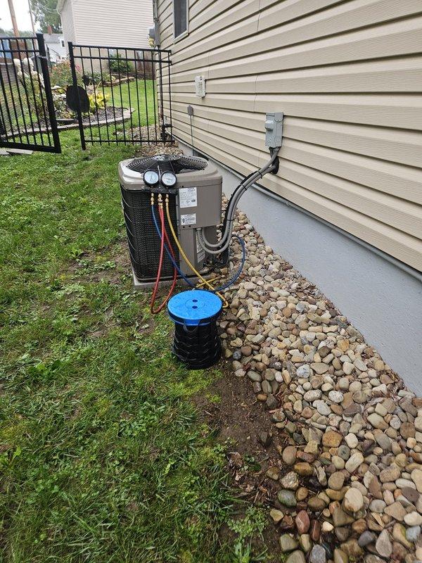 Responded to frozen refrigerant line complaint at residential property. Upon arrival, found ice formation on refrigerant lines at elbow connection entering structure from outdoor condensing unit. Performed diagnostic evaluation of complete system including outdoor unit with multi-colored refrigerant lines and indoor air handler with condensate pump. Inspected airflow, refrigerant pressures, and system operation to determine root cause of freezing condition, which typically indicates restricted airflow, low refrigerant charge, or inadequate system cycling.