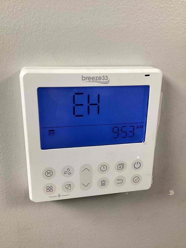 Responded to EH error code displaying on Breeze33 thermostat for new pharmacy HVAC unit. Inspected blower motor assembly (Model ZKFD-750-10-4, Serial A0000765) and verified proper installation and operation. Cleared fault code, confirmed system returned to normal operation with thermostat displaying correctly.