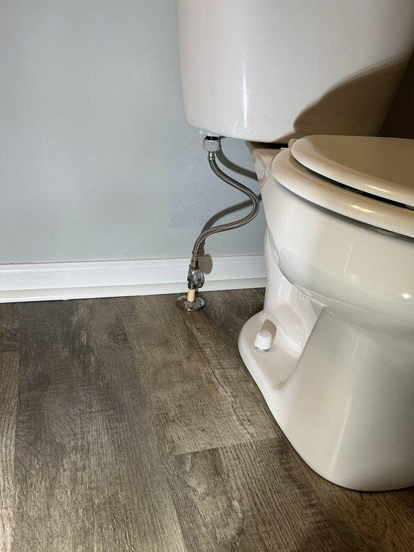 Responded to a water leak originating from a second-floor toilet that was causing damage to the ceiling below. Upon inspection, identified the fill valve assembly as the source of the leak, with visible mineral deposits and wear on the internal tank components. Documented the wall-mounted tank system, water supply connections, and shutoff valve configuration, noting the Mansfield toilet tank model and existing plumbing setup for potential repair or replacement of the faulty fill valve mechanism.