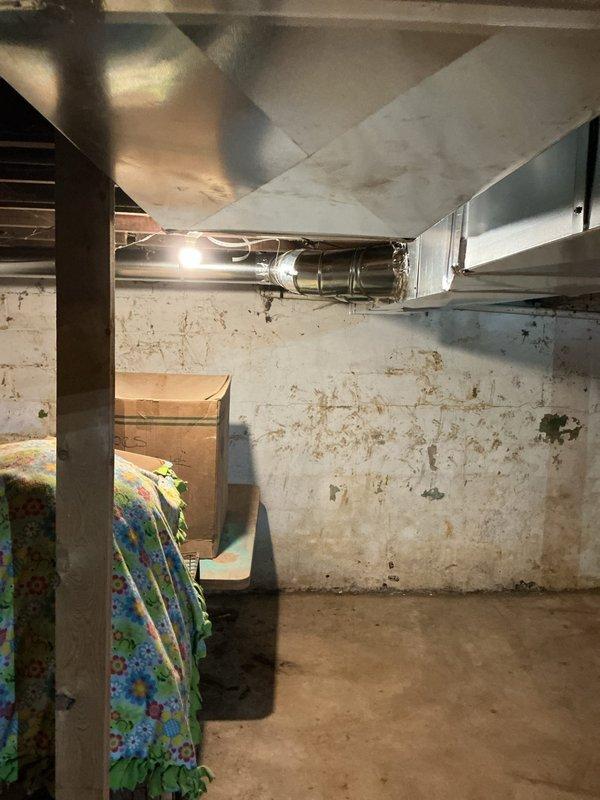 Completed new construction HVAC installation in basement utility area, including furnace and complete ductwork system. Installed horizontal metal supply ductwork running across exposed ceiling joists with proper register placement, ensuring adequate airflow distribution throughout the structure. All components installed to code specifications and system tested for proper operation.