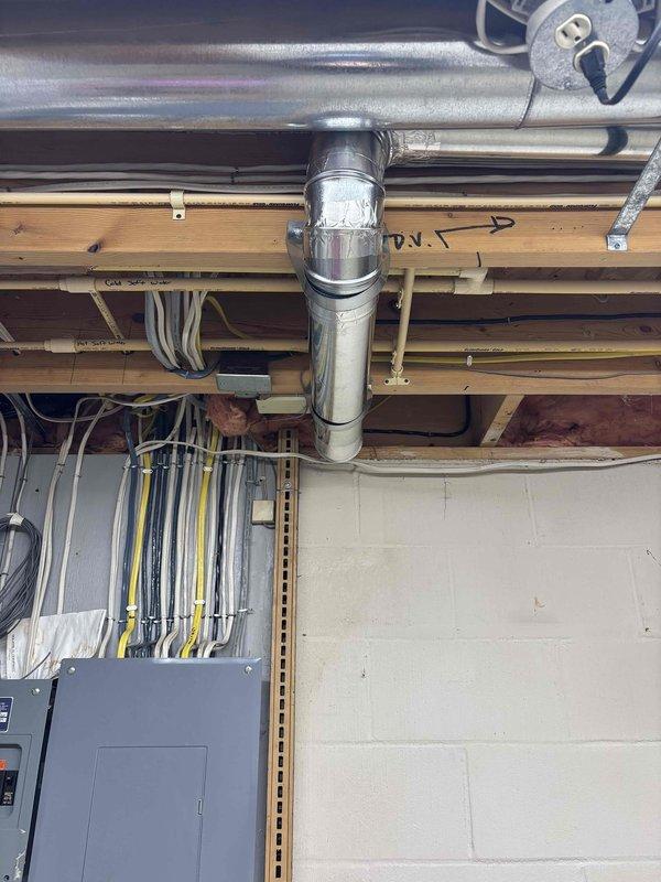 Relocated dryer vent to new position as requested, routing flexible ductwork through basement ceiling joists to accommodate revised floor plan layout. Secured all ductwork connections and verified proper venting pathway from appliance location to exterior termination point.