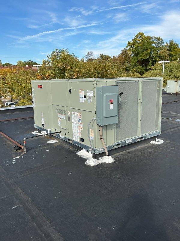 Completed installation of a Trane 17.5-ton rooftop unit on a commercial building with proper mounting, electrical disconnect, and weatherproofing. The RTU was secured to the roof structure with support pads and mounting brackets, with all penetrations sealed appropriately. Unit was positioned, leveled, and verified operational with all safety labels and specifications clearly visible on the equipment.