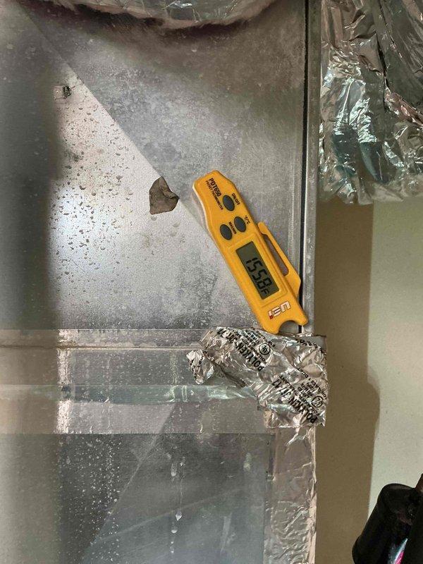 Performed scheduled commercial heating maintenance on an Armstrong Air upright gas furnace, inspecting the cabinet, flue and condensate piping, gas line with shutoff valve, and connected supply ductwork. Noted heavy condensation on the galvanized duct surface with a measured surface temperature of 55.8°F, along with peeling foil tape at a duct seam, indicating a need for insulation and seam sealing to prevent moisture accumulation and potential damage. Recommend re-sealing the duct seams and insulating the affected ductwork.