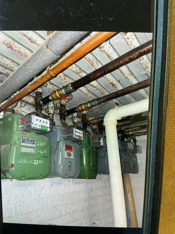 Installed shutoff valves on the gas piping serving a multi-meter manifold in the basement utility area, connecting flexible gas lines with brass fittings and red-handled isolation valves to each meter. Verified secure connections and proper valve operation at each meter location, with piping routed overhead to the meter bank.