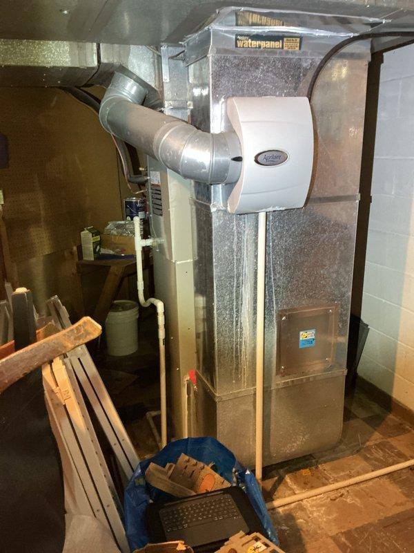Performed an on-site evaluation for replacement of an existing upright gas furnace, documenting the PVC condensate and venting runs, galvanized supply plenum, and flexible duct connections. Noted the plenum-mounted Aprilaire humidifier and adjacent water heater, with no visible rust, frost, or leaks, and confirmed the unit's location, clearances, and ductwork configuration to support an accurate replacement and retrofit estimate.