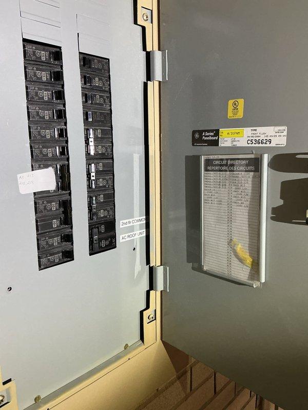 Performed an on-site assessment for a commercial multi-zone mini split system installation consisting of three outdoor units and nine indoor units. Inspected the existing rooftop mounting area and Mitsubishi Electric condensing units, and evaluated the available electrical service, including a GE A Series panelboard with labeled circuits for the 2nd floor commons and rooftop AC unit, to determine breaker capacity and circuit requirements. Documented existing equipment placement, support blocking, and refrigerant line routing conditions to support system sizing and installation planning.
