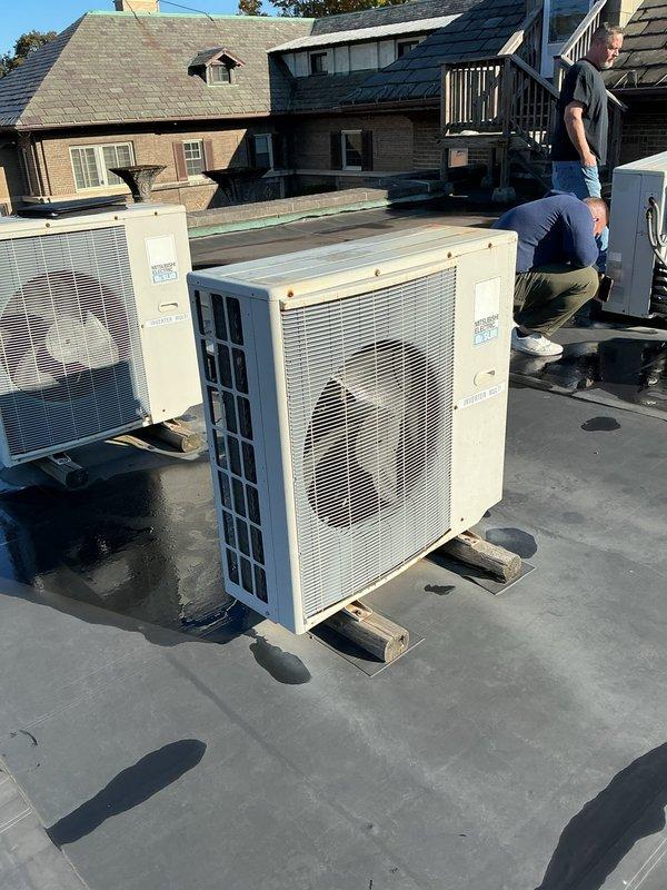 Performed an on-site assessment for a commercial multi-zone mini split system installation consisting of three outdoor units and nine indoor units. Inspected the existing rooftop mounting area and Mitsubishi Electric condensing units, and evaluated the available electrical service, including a GE A Series panelboard with labeled circuits for the 2nd floor commons and rooftop AC unit, to determine breaker capacity and circuit requirements. Documented existing equipment placement, support blocking, and refrigerant line routing conditions to support system sizing and installation planning.