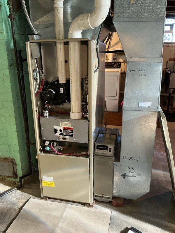 Performed an on-site evaluation for replacement of an existing upflow gas-fired forced-air furnace in the basement mechanical area, inspecting the cabinet interior, blower/inducer assembly, wiring, control board, burner compartment, and PVC combustion venting. Assessed the supply plenum and ductwork, the 16x25x4 media filter housing, and the Honeywell air cleaner to determine retrofit and sizing requirements for the new equipment. No visible rust, frost buildup, or physical damage was observed on the unit, and findings were documented with photographs to support the replacement estimate.