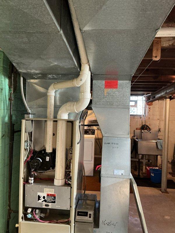 Performed an on-site evaluation for replacement of an existing upflow gas-fired forced-air furnace in the basement mechanical area, inspecting the cabinet interior, blower/inducer assembly, wiring, control board, burner compartment, and PVC combustion venting. Assessed the supply plenum and ductwork, the 16x25x4 media filter housing, and the Honeywell air cleaner to determine retrofit and sizing requirements for the new equipment. No visible rust, frost buildup, or physical damage was observed on the unit, and findings were documented with photographs to support the replacement estimate.