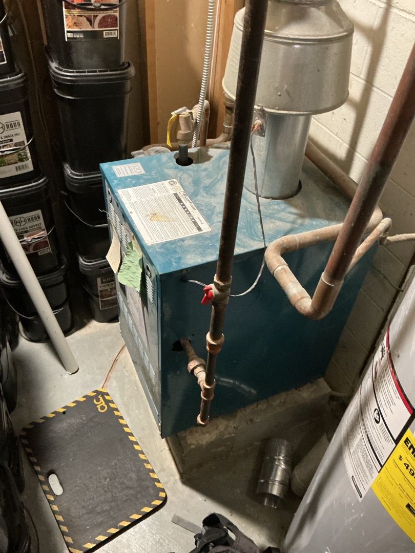 Upon arrival, I was greeted by Christina. She showed me to the boiler in the basement and to the two thermostats.

I determined that the thermostat in the basement controls the electric baseboard heat for the basement only. The thermostat near the kitchen controls the boiler.

I turned the thermostat up. The exhaust damper opened and the water pump turned on but the burners never lit. I found the pilot was out. I tried to relight it but the flame is weak and won’t stay lit and the pilot assembly/thermocouple and burners need cleaned.

I quoted on pulling and cleaning the burners and pilot assembly to see if the unit will light. Customer approved.

I pulled and cleaned them and then reassembled. I lit the pilot. Flame was good but it still wouldn’t stay lit. I checked the millivolt read on the thermocouple. It was within specs. I tried putting on a new thermocouple but it still won’t stay lit. The gas valve has failed. The pilot valve coil has failed. Need to replace the gas valve. I re