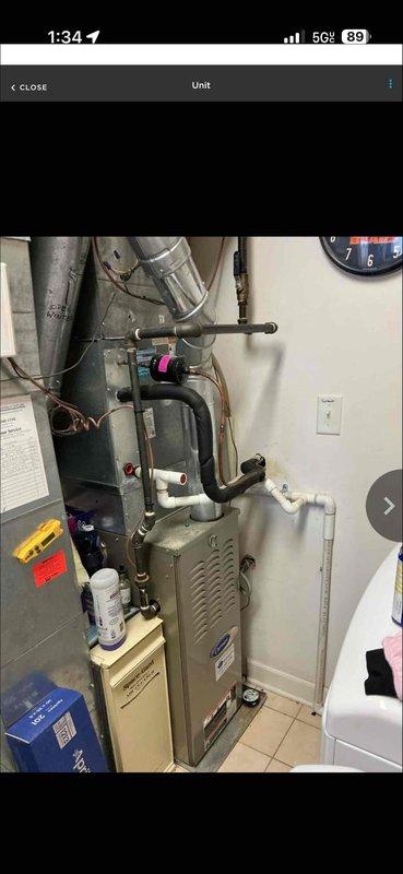 Performed assessment of 14-15 year old furnace system located at rear of property. Documented existing installation including Aprilaire 700M humidifier mounted to ductwork and connected to water supply. System evaluation indicated replacement would be more cost-effective than continued repairs given the unit's age and condition.