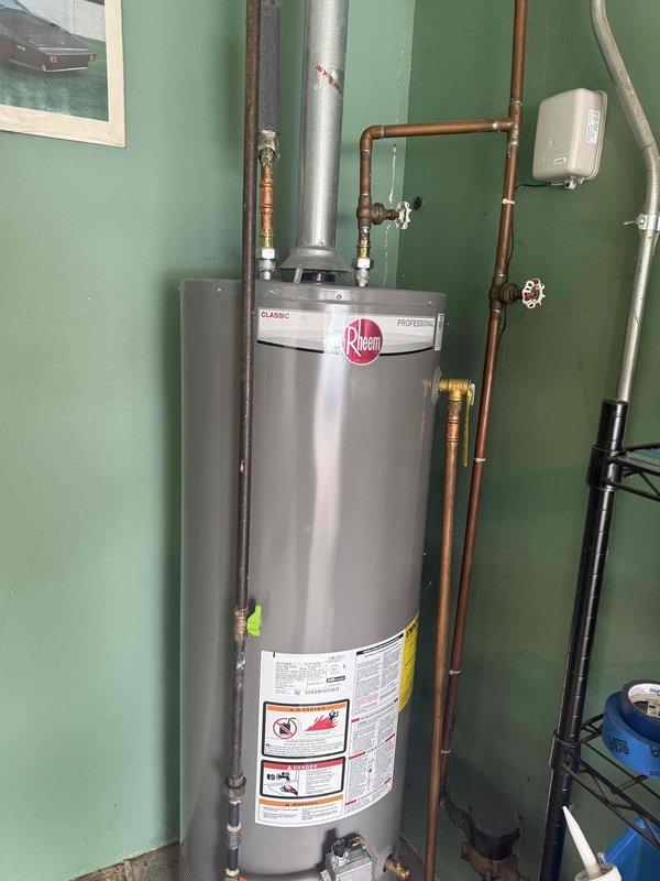 Provided estimate for replacement of existing Rheem Classic Professional gas water heater with a Navien or Rinnai tankless system in garage location. Current installation includes standard copper supply/return lines, metal flue pipe, and associated valves. Tankless conversion would require reconfiguration of existing plumbing connections and electrical components.