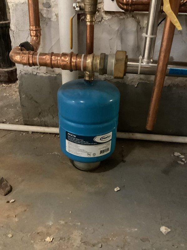 Performed routine maintenance inspection on boiler and water heater per service agreement. Examined expansion tanks (blue PROFLO tank and green pressure tank) connected to copper plumbing system. Both tanks appear to be functioning properly with no signs of leakage at connection points, though noted some moisture staining on nearby wall that should be monitored.
