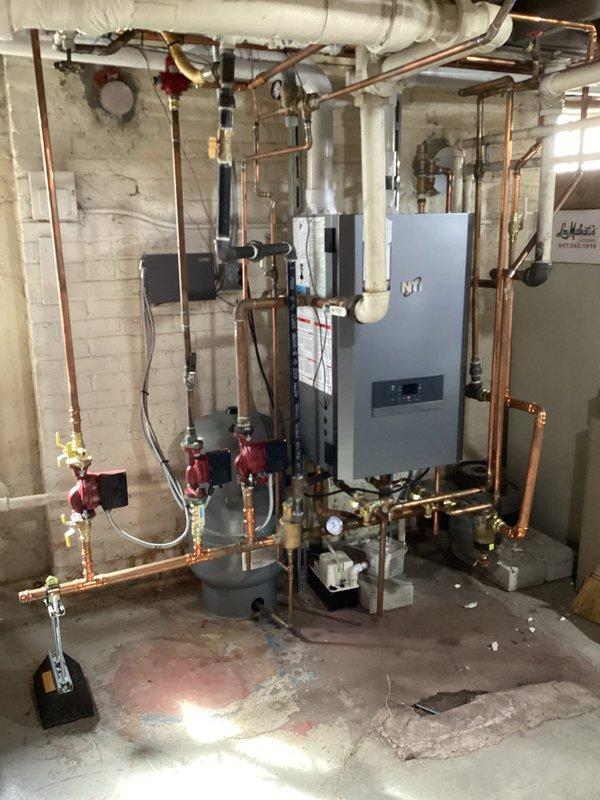 Responded to emergency service call for an inoperative 2-year-old NTi boiler system. Diagnosed and repaired system failure, restoring proper heating function to the residence. Documented complete heating system configuration including circulation pumps, copper piping network, and ventilation components.